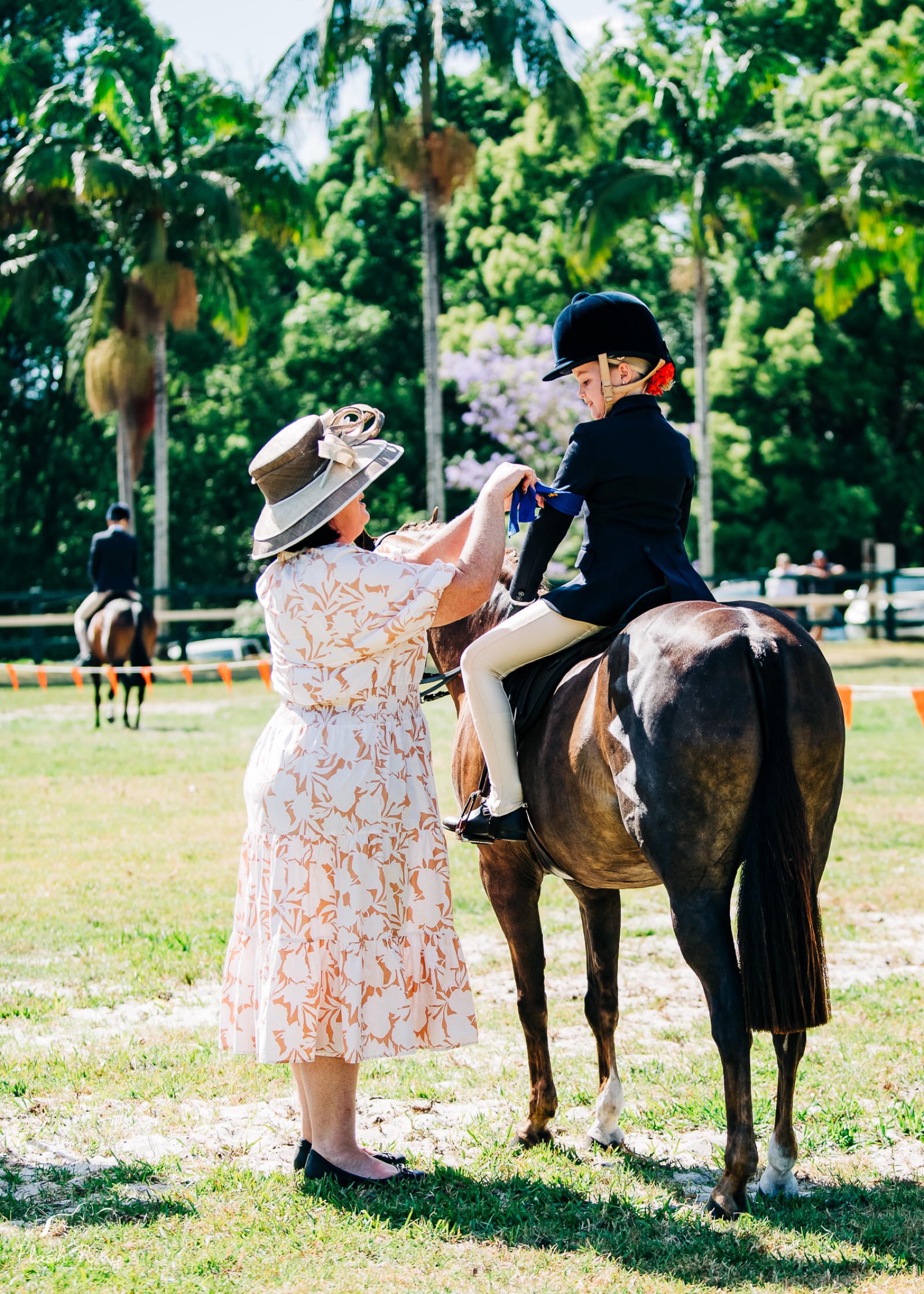 Mother adjusting young rider before event